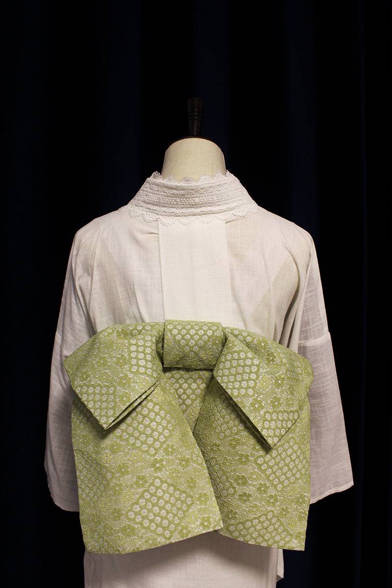 Back view of kimono waist seal styling bow in green lace, neatly tied and centered on a traditional white kimono.