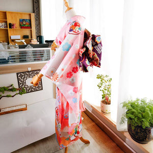 Side view of pink floral kimono with purple big three-leaf bow belt. Swinging sleeves and geisha-style belt enhance traditional style.