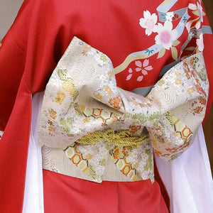 Gold floral brocade bow belt styled with red kimono, ideal for traditional Japanese yukata waist styling and festive fashion shoots.