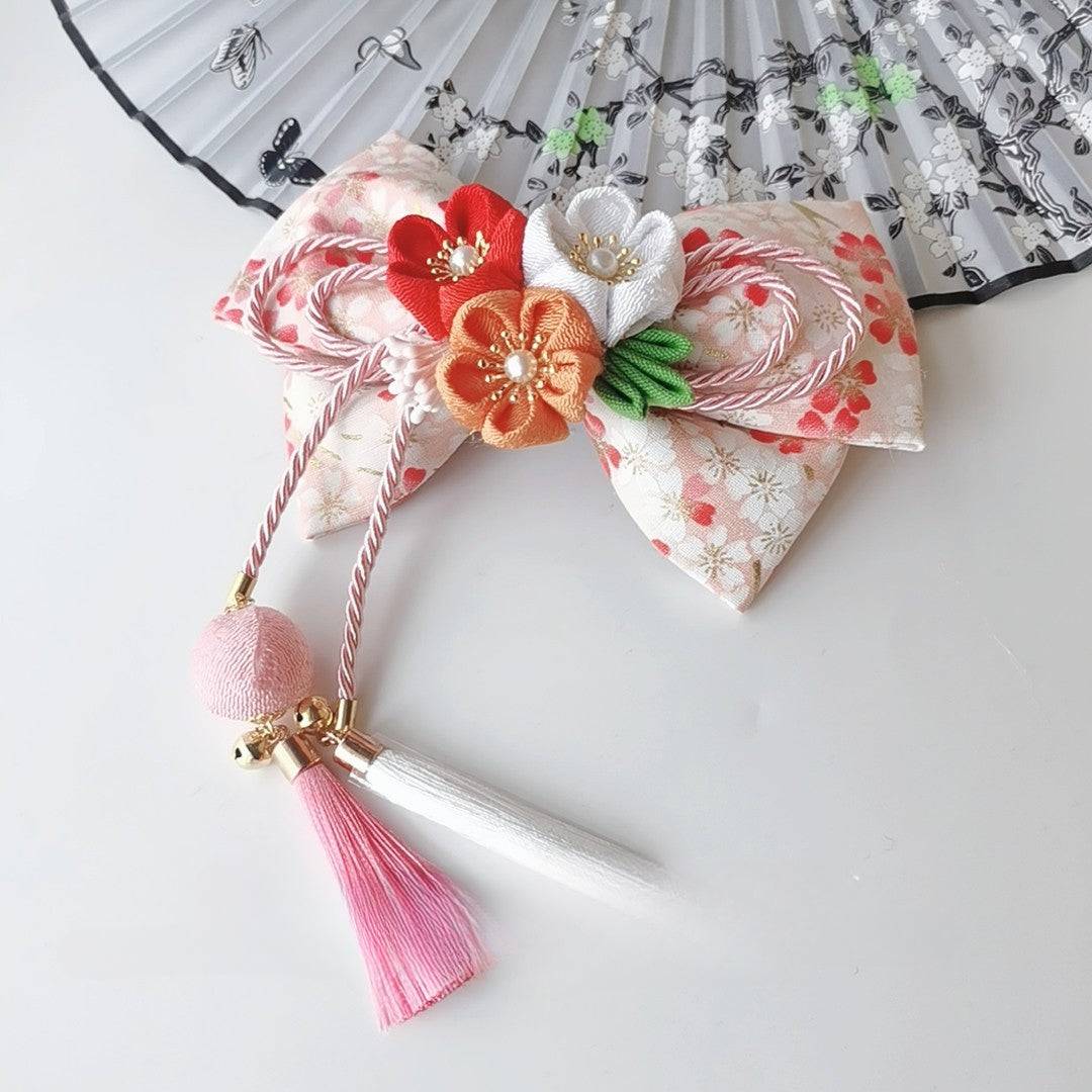 Cream floral Japanese kimono hair clip with orange and white cherry blossoms, fine bow work, and pink tassel.