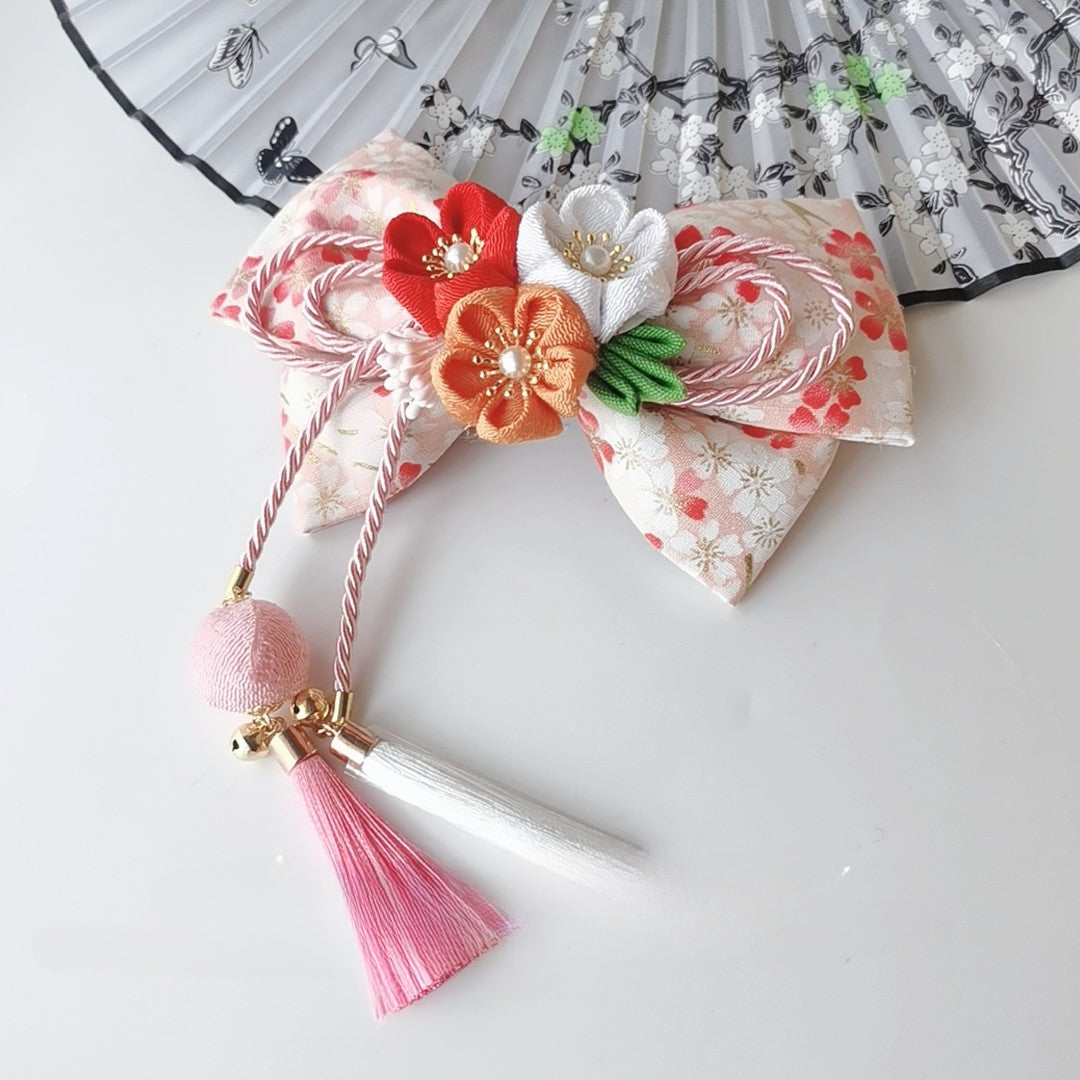 Peach floral Japanese kimono hair clip with orange and white cherry blossoms and pink-white tassel detail.