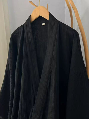 Side view of the black cotton gauze robe with wide sleeves and flowing hem