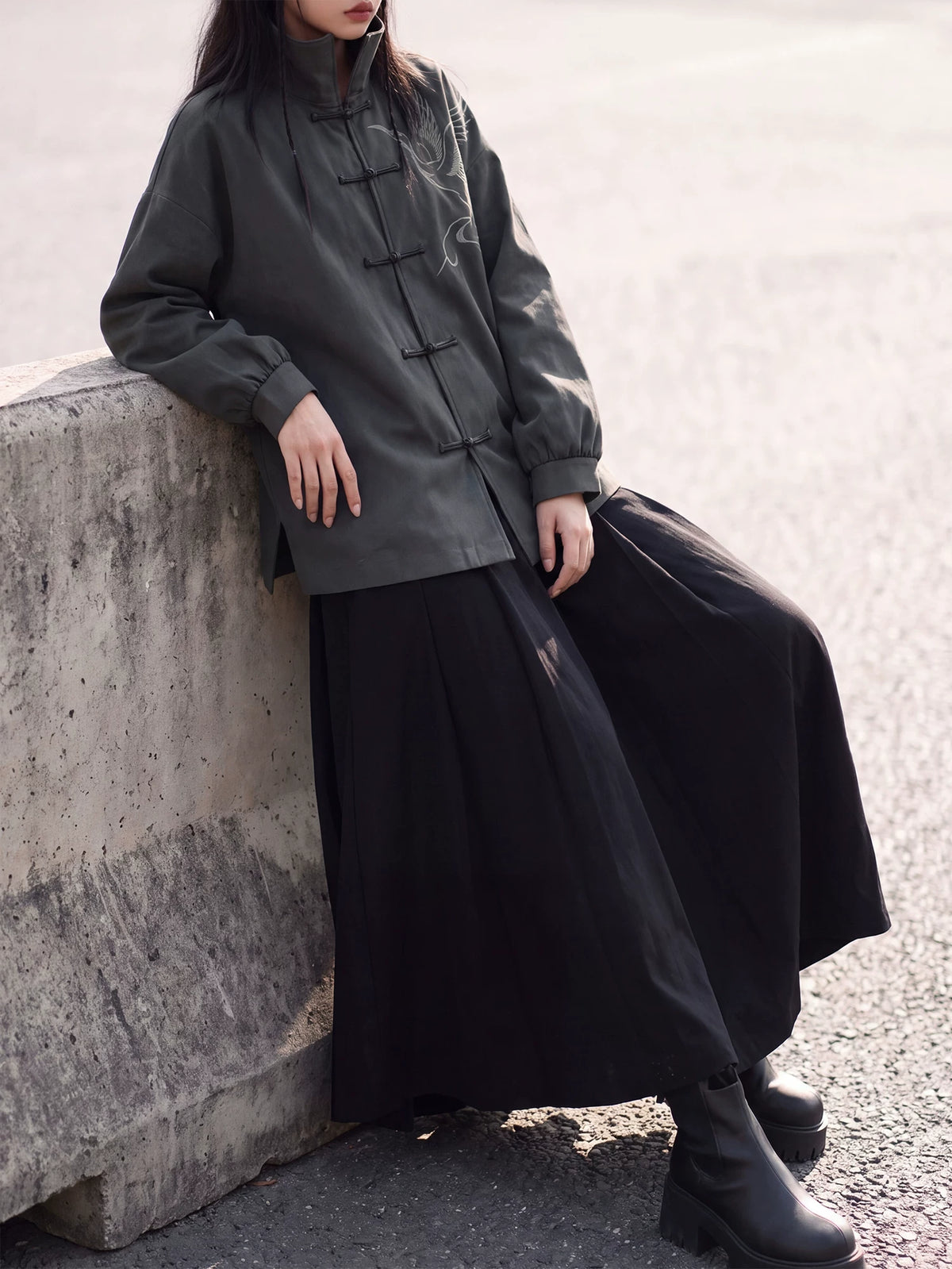 Charcoal crane jacket styled with a black skirt beside a wall