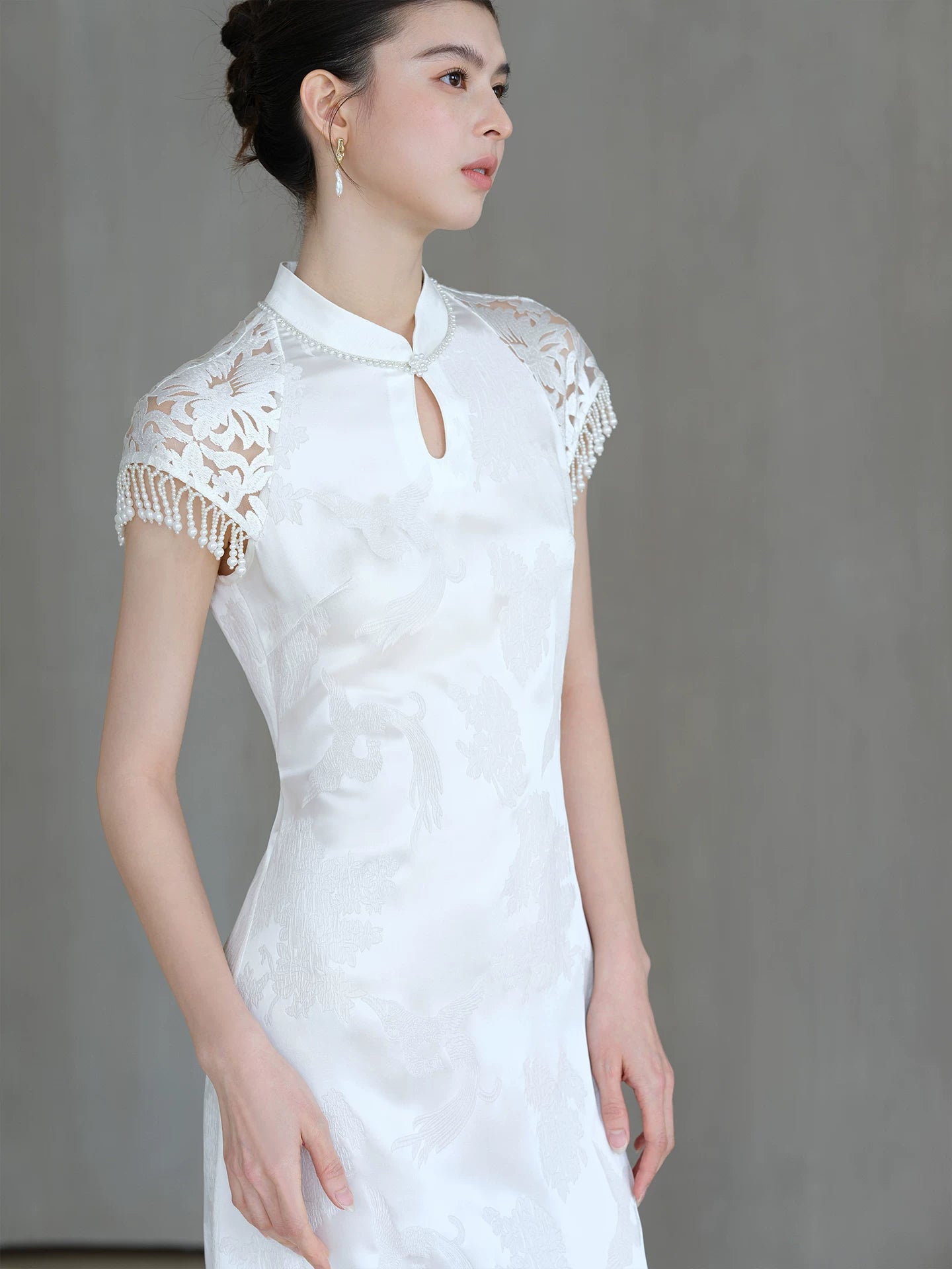 Front styling view of the Crane White cutwork tassel qipao dress, with cutwork detailing, tassel accents and a graceful modern cheongsam shape.