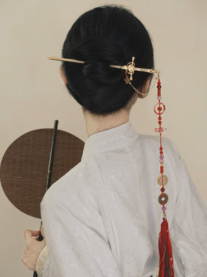 Gold sword hairpin with red tassel and coin charms, styled in a traditional bun for a classic Chinese Hanfu appearance.