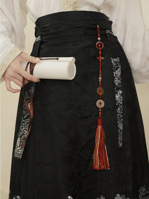 Red and gold tassel hairpin used as a decorative waist charm on a black Hanfu skirt, blending ancient style with modern wear.