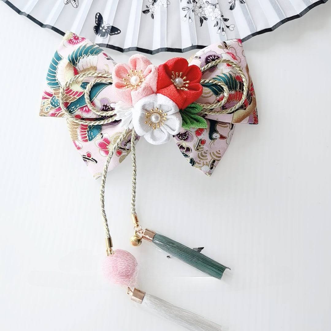 Elegant Japanese kimono hair accessory in pink and gold with red and white cherry blossoms and green tassels.