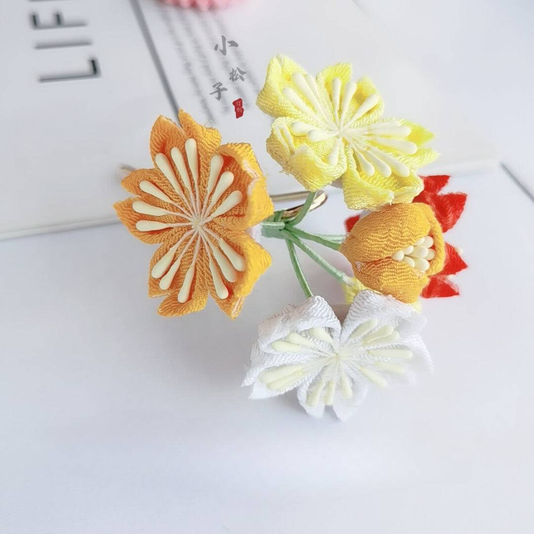 Side view of multicolor cherry blossom hairpin with yellow, orange, and white petals, part of Japanese accessory set.
