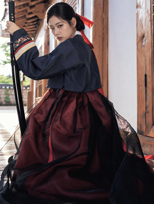 Back view of navy jacket and flowing burgundy Hanbok skirt