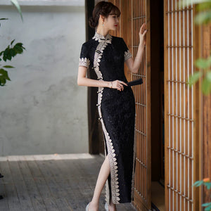 Side pose in a black lace qipao showing the fitted waist and high slit with pale trim