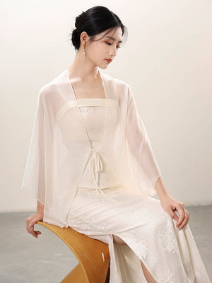 White embroidered slip dress and sheer outer layer styled to show its fit and drape, including embroidered slip dress, translucent outer layer and soft layered drape.