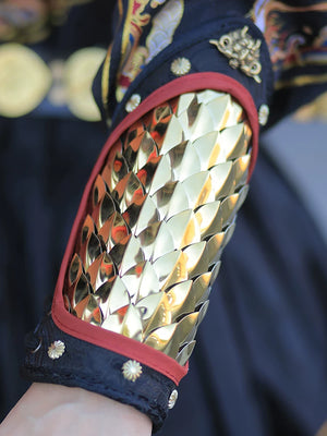 Close view of polished gold overlapping metal scales and red piping on the Hanfu arm guard