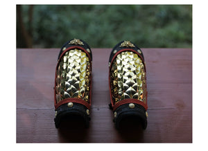 Close-up of gold scale armor panel fitted along the forearm with adjustable side lacing