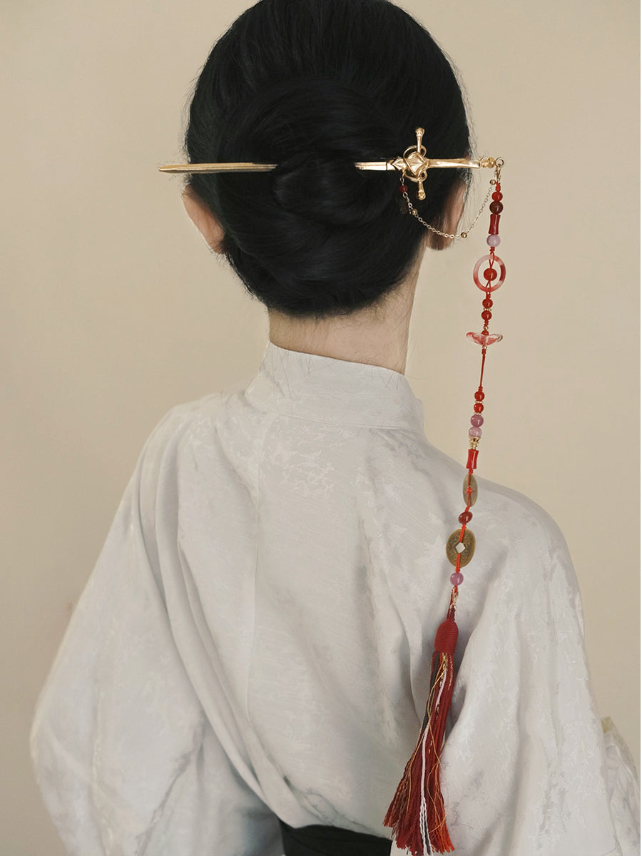 New Chinese style sword spike tassel hairpin with red beads and gold detailing, worn in a traditional bun hairstyle for Hanfu fashion.