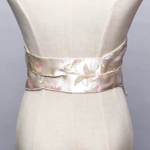 Back view of a white brocade kimono belt seal with pink and green floral embroidery, elegantly styled on a mannequin.