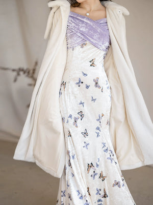 Detailed view of a white fur jacket layered over a butterfly-printed velvet fishtail skirt with a purple bodice.