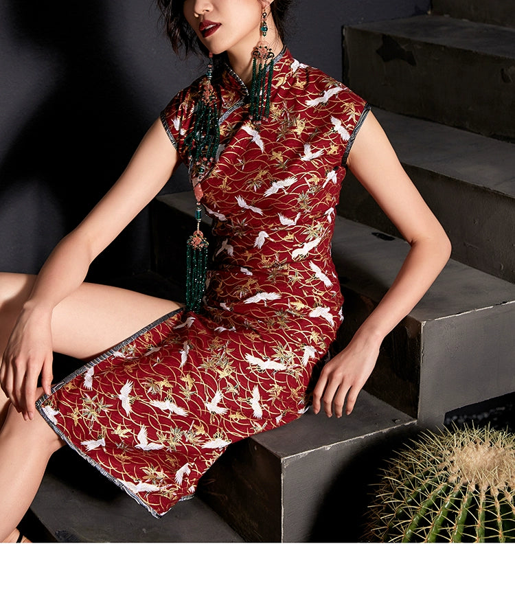 Model seated in red cheongsam with crane print and stylish split skirt.