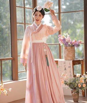 Woman wearing a pink hanbok dress, holding a flower in a serene setting. A beautiful representation of Korean heritage.