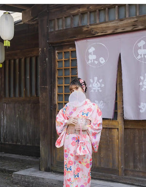 Close-up of pink floral fabric with cherry blossom patterns, showcasing the intricate design of the Japanese kimono.