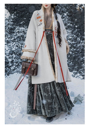 Front view of white woolen Hanfu coat with red ribbon ties, floral embroidery, and faux fur trim, styled with a green pleated skirt.