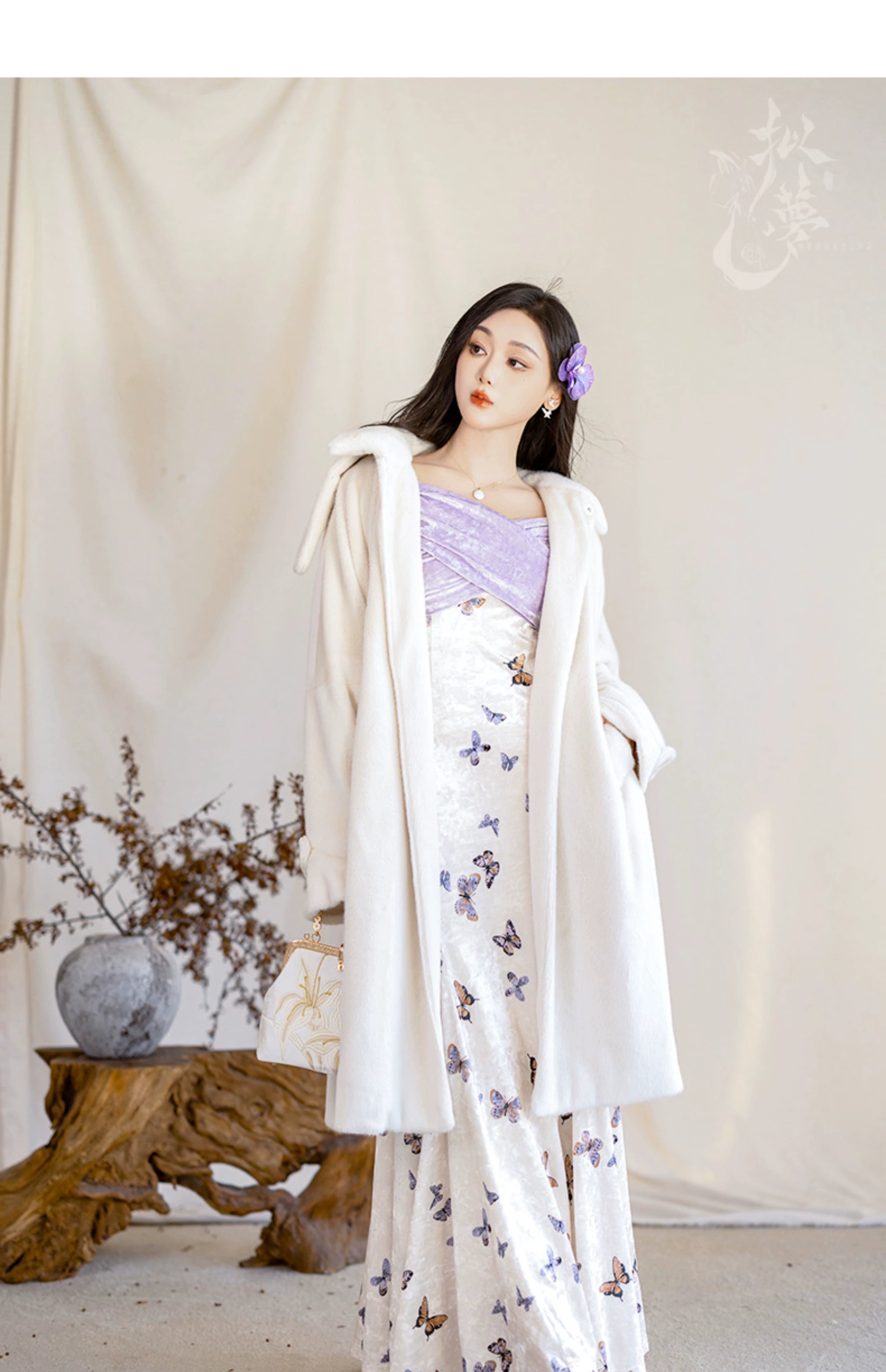 Stylish winter outfit featuring a white eco-friendly fur jacket over a butterfly-printed fishtail skirt with a purple bodice.