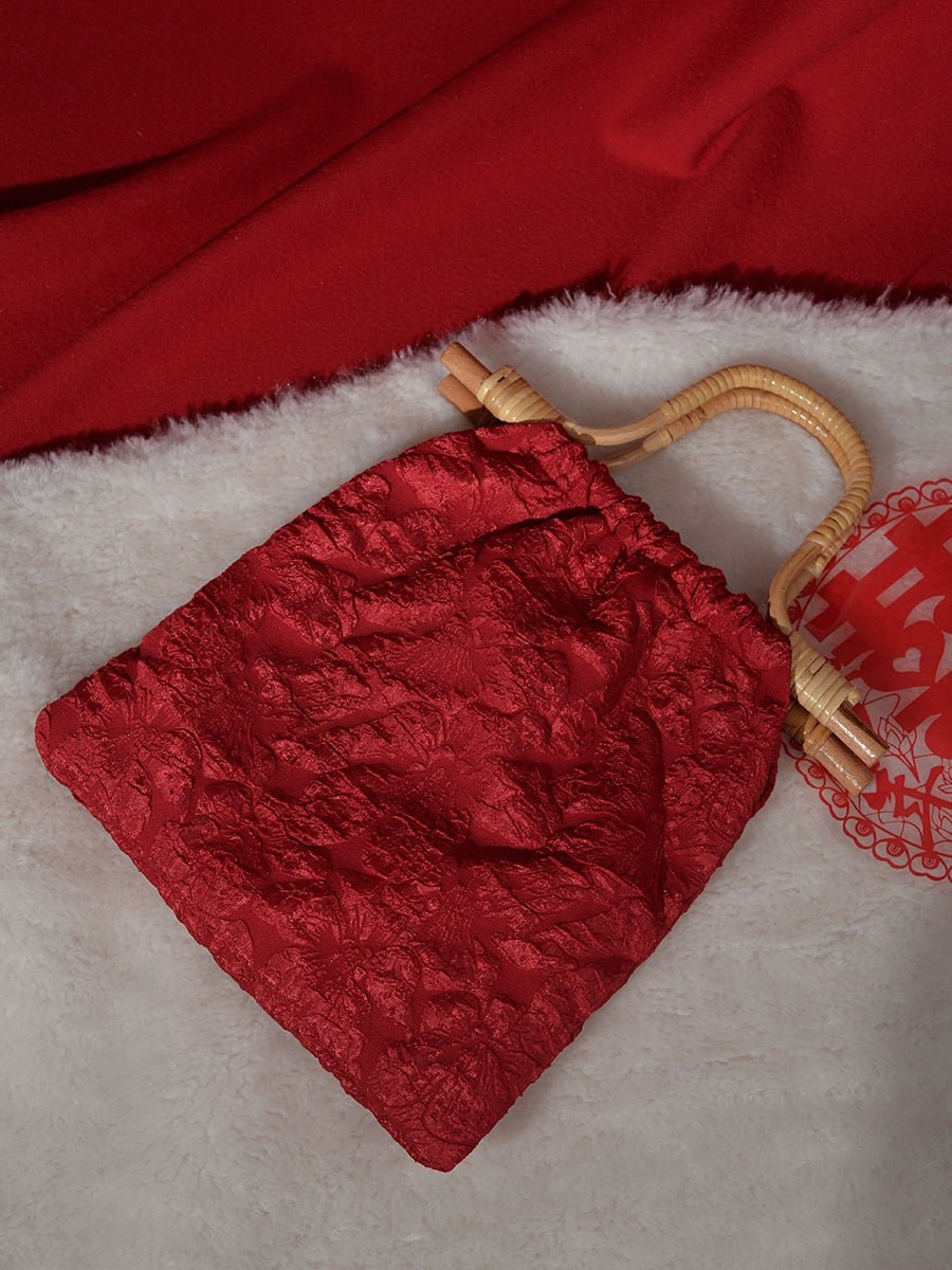 Flat-lay of a red floral-patterned wedding bag with bamboo handle, ideal for brides seeking a chic and practical accessory.