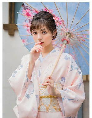 Close-up of a woman in a pink crane-patterned yukata kimono, holding a parasol, highlighting the elegant Japanese design.