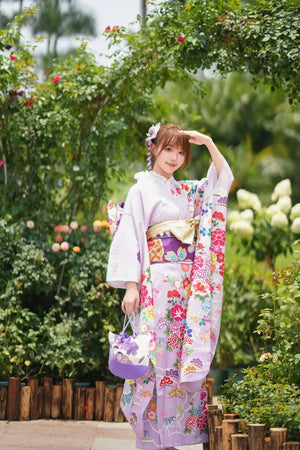 Japanese kimono with pastel floral prints and big sleeves, styled with a matching handbag, set in a lush garden setting.