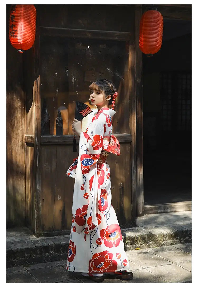 Side view of a woman in a white and red floral Japanese kimono dress, styled with an obi belt, walking in a traditional Japanese street.