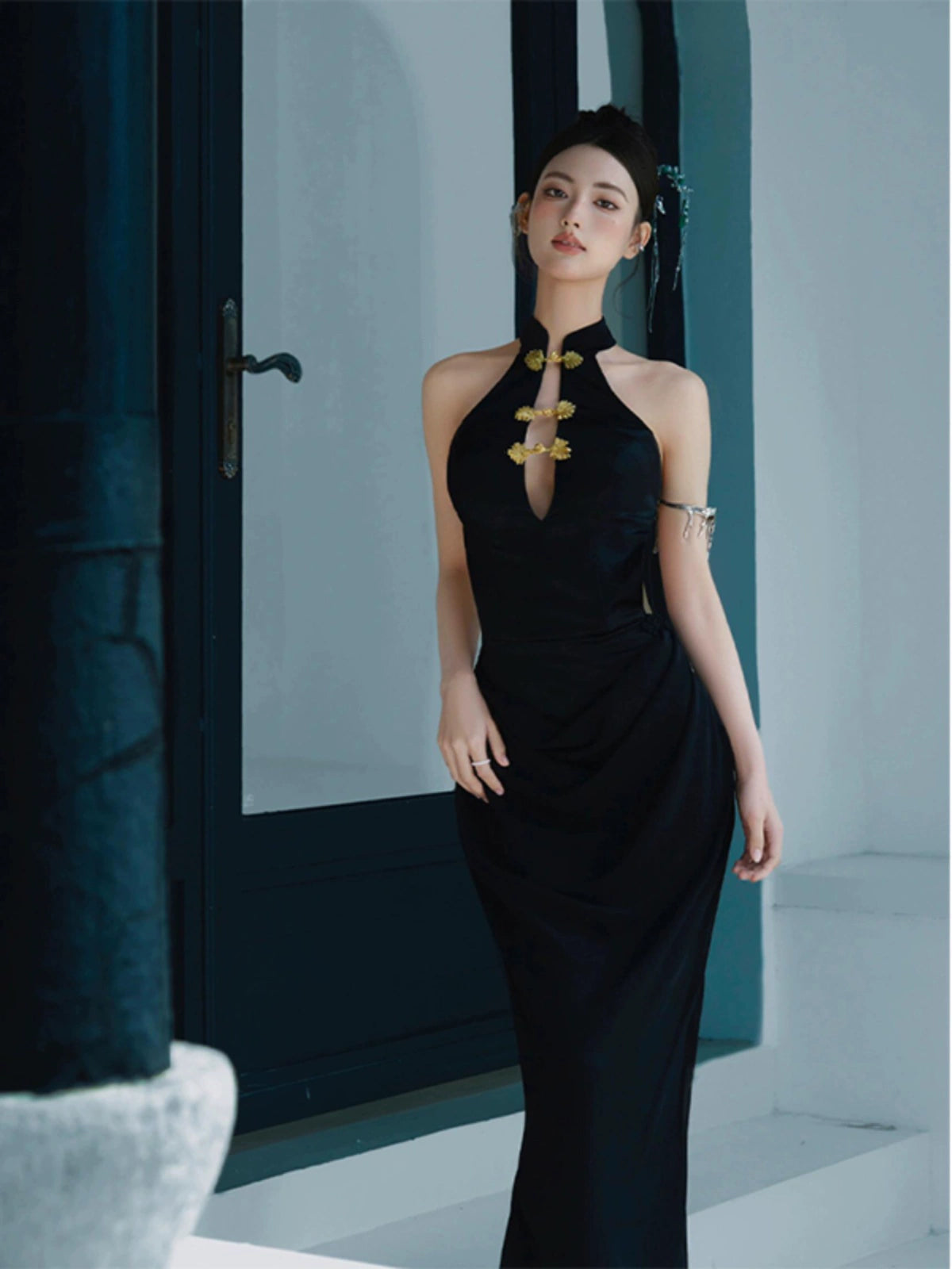 Sophisticated black fishtail cheongsam dress featuring a halter neckline and gold floral details, styled for evening wear.