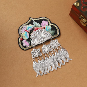Handmade Guizhou Miao fridge magnet with black embroidered base and silver fish fringe, showcasing traditional ethnic craftsmanship.