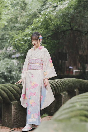 Retro-style white kimono with floral patterns, worn in a peaceful outdoor setting.