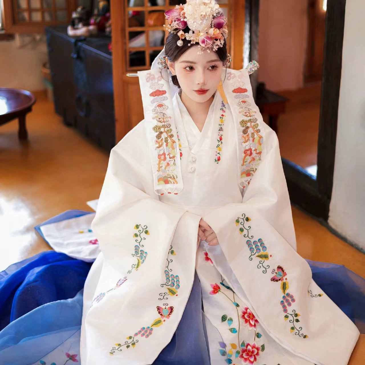 Elegant white Korean wedding hanbok with colorful floral embroidery.