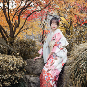 Vintage-style pink yukata dress with floral motifs, worn in a traditional garden.