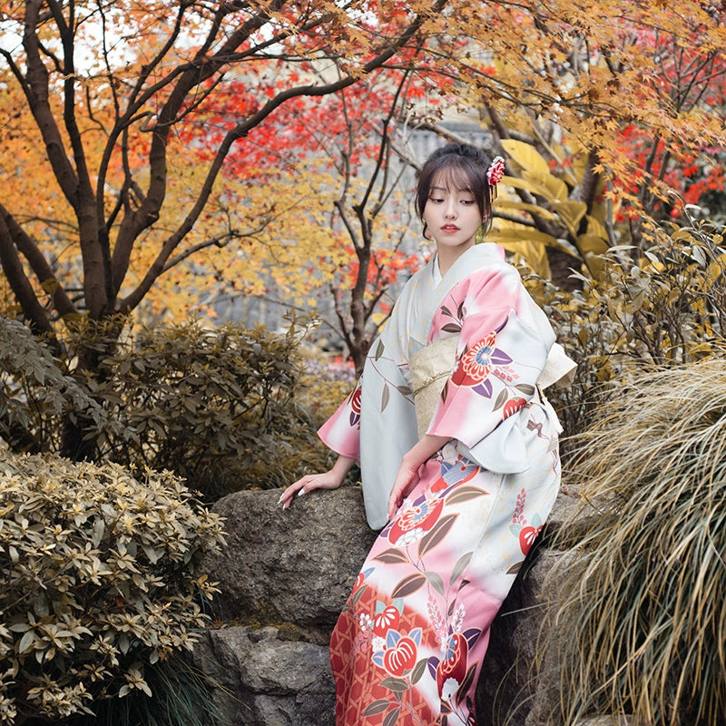 Vintage-style pink yukata dress with floral motifs, worn in a traditional garden.