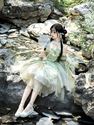 Model seated in garden wearing Green Lolita Dress with butterfly and flower details, ideal for summer cosplay or themed shoots.