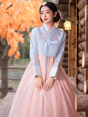 Graceful traditional Korean hanbok in blue and pink, featuring delicate floral embroidery and a flowing skirt.