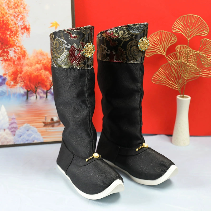 Stylish black Hanfu wedding boots for men with gold embroidery and decorative buttons, displayed with a festive background.