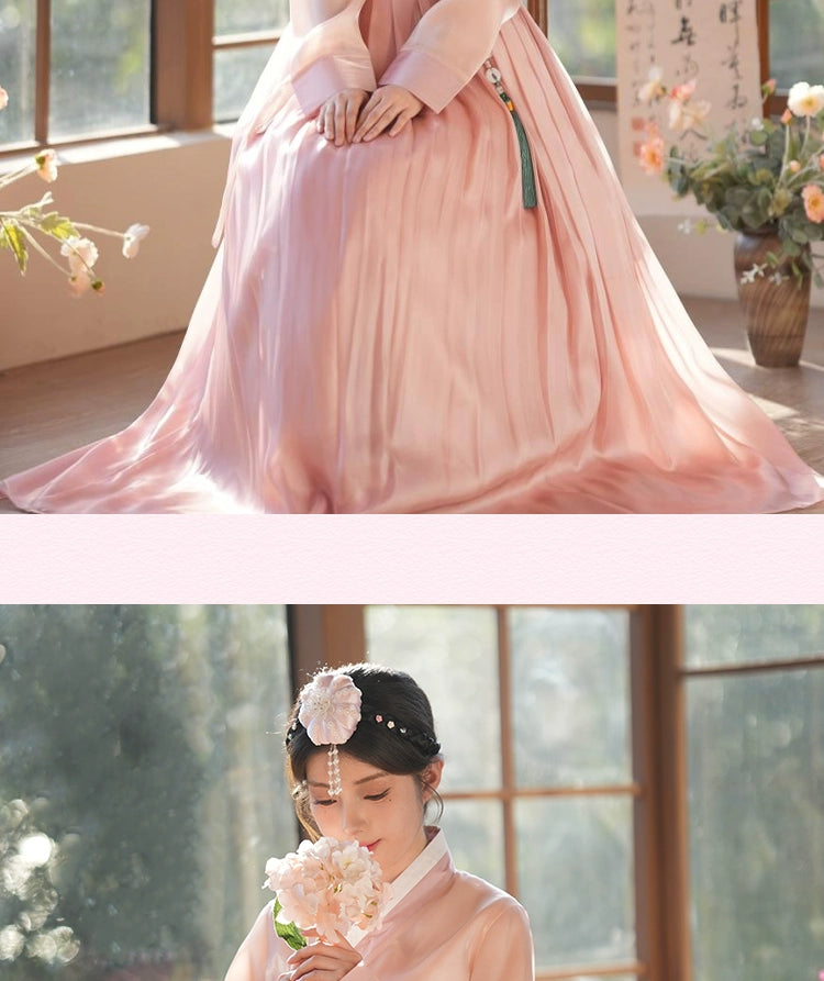 Elegant hanbok dress in a lotus root pink shade, styled with a floral hairpiece. A perfect choice for weddings and celebrations.