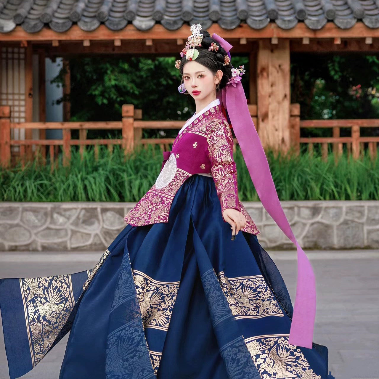 Traditional Korean Hanbok with vibrant pink and blue design, worn outdoors.