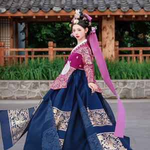 Traditional Korean Hanbok with vibrant pink and blue design, worn outdoors.