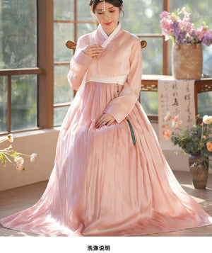 Woman in a pink hanbok dress, seated gracefully in a traditional setting. A stunning representation of Korean heritage and elegance.