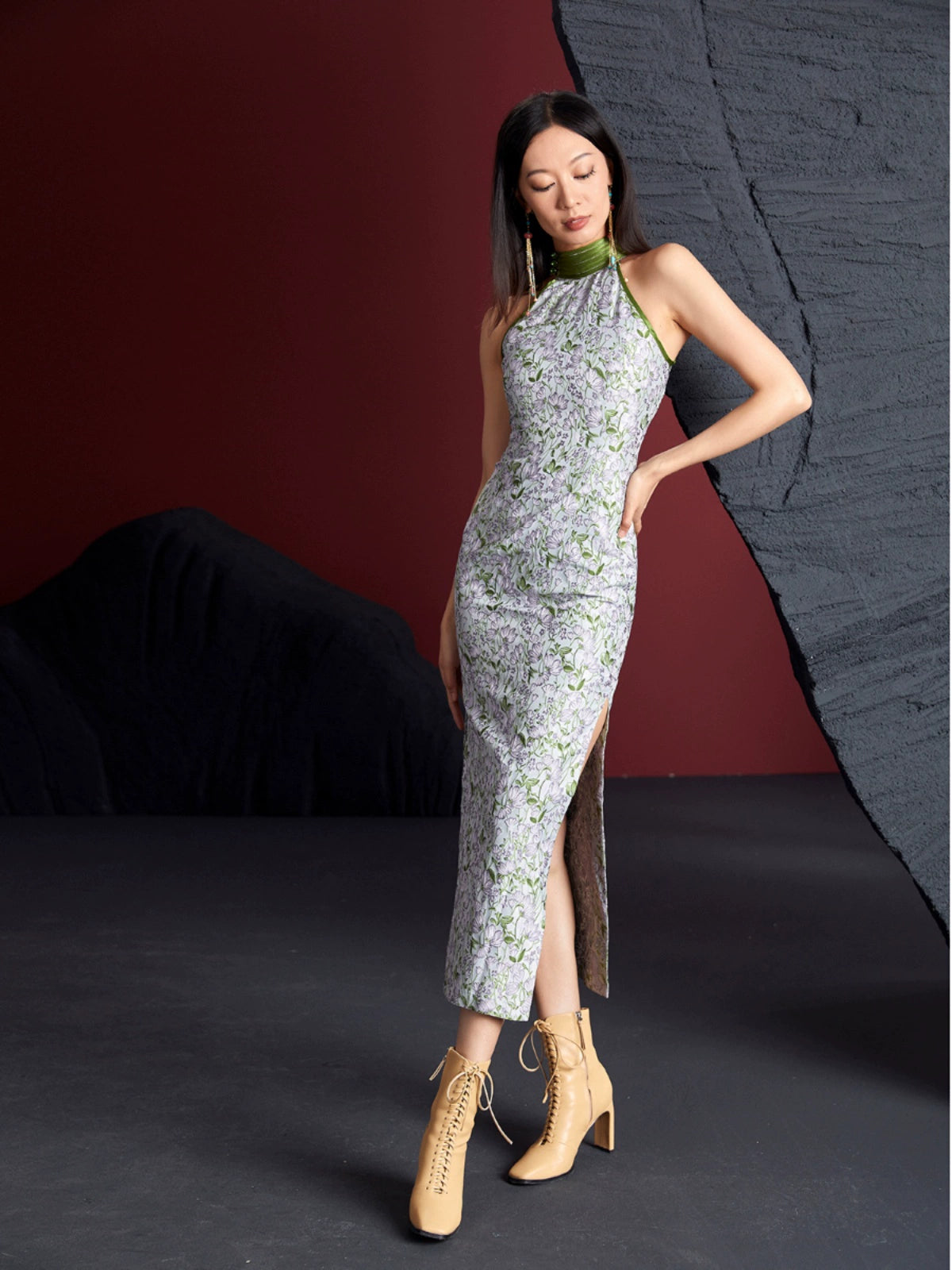 Retro sleeveless cheongsam with green floral jacquard fabric, high slit, and mandarin collar. Styled with beige lace-up boots.