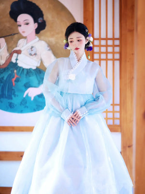 Elegant blue Hanbok dress with traditional Korean art in the background.