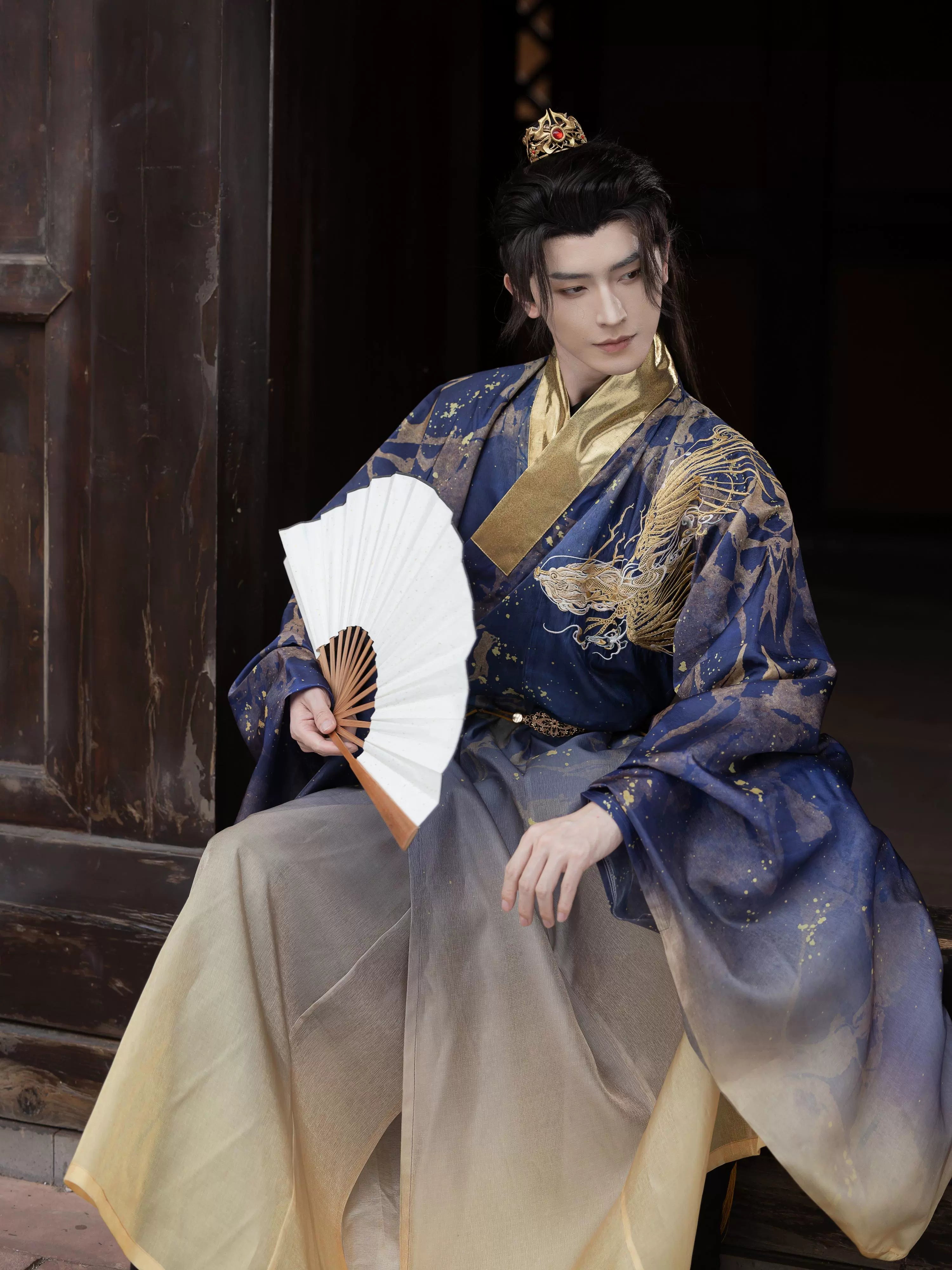 Hanfu Printing Smudge - Dragon Roar Daoist Robe in Ming blue with intricate embroidery, worn by a model holding a white folding fan.