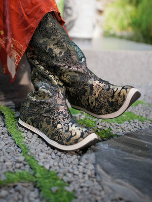 Side view of Dragon boots featuring gold embroidery on black fabric, styled with a red Hanfu robe, highlighting traditional craftsmanship.