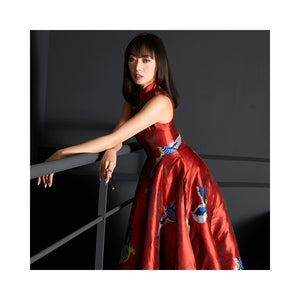 Model leaning on railing wearing a red brocade jacquard cheongsam dress.