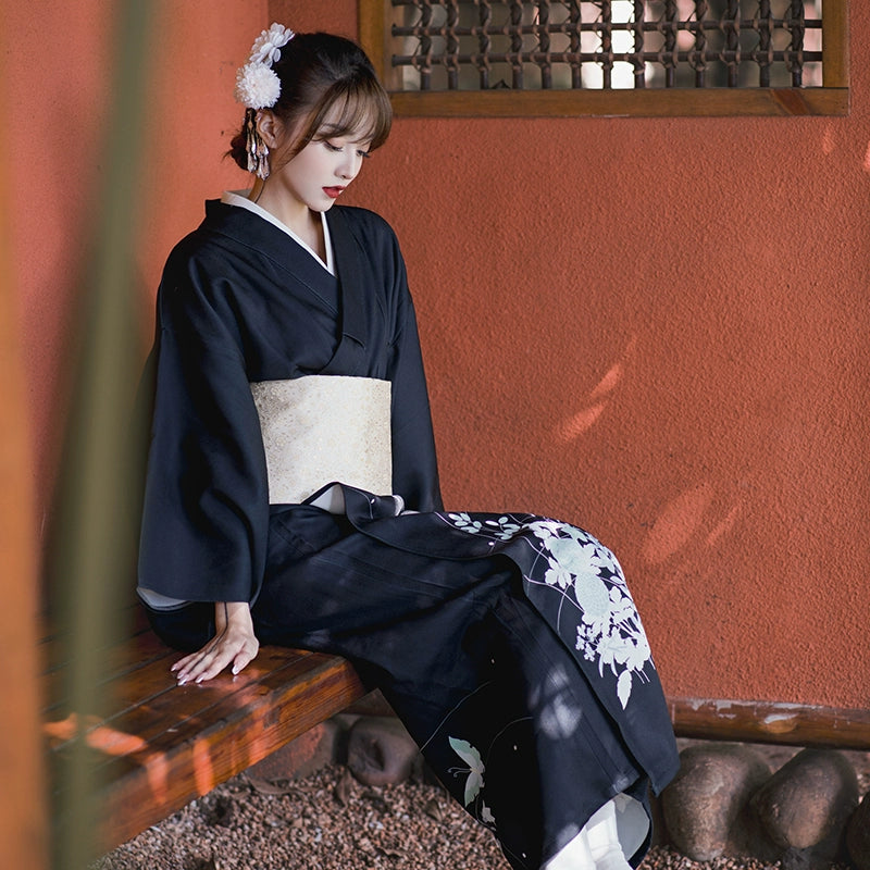 Elegant black yukata dress with butterfly and floral design, worn with a gold obi.