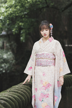 Close-up of a white floral kimono with pastel obi, worn in a serene forest environment.