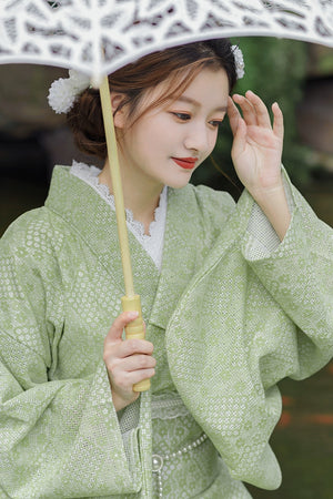 Model in green kimono dress with lace parasol by a koi pond.